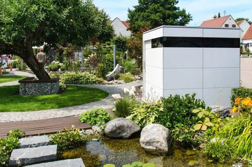 Weisses modernes Gartenhaus in schönem Garten mit Teich.