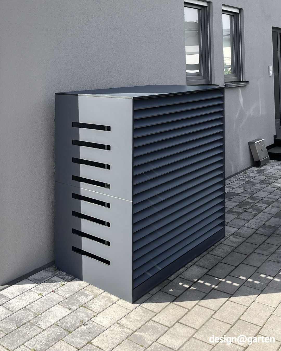 Seitliche Lufteinlässe und Lamellen für Luftzirkulation in grauer Verkleidung für Wärmepumpe