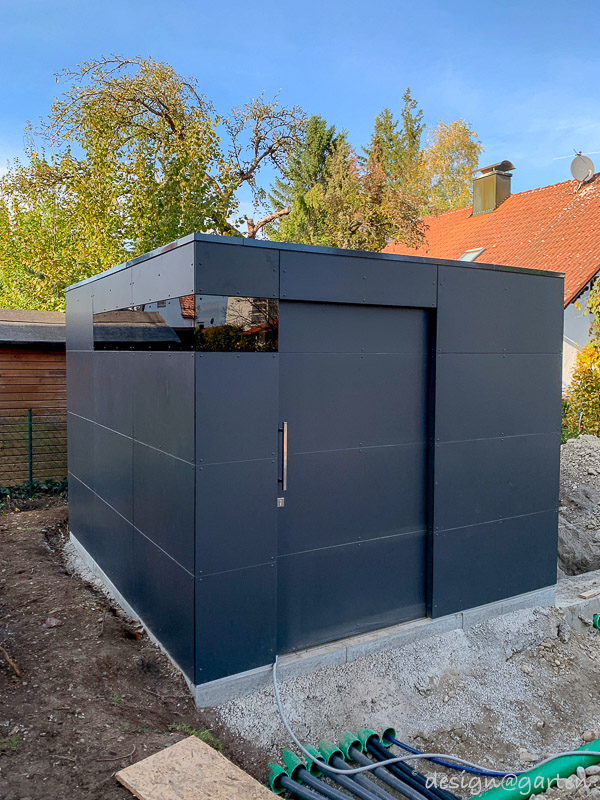 Moderna caseta de piscina con techo plano como núcleo técnico en Landsberg am Lech