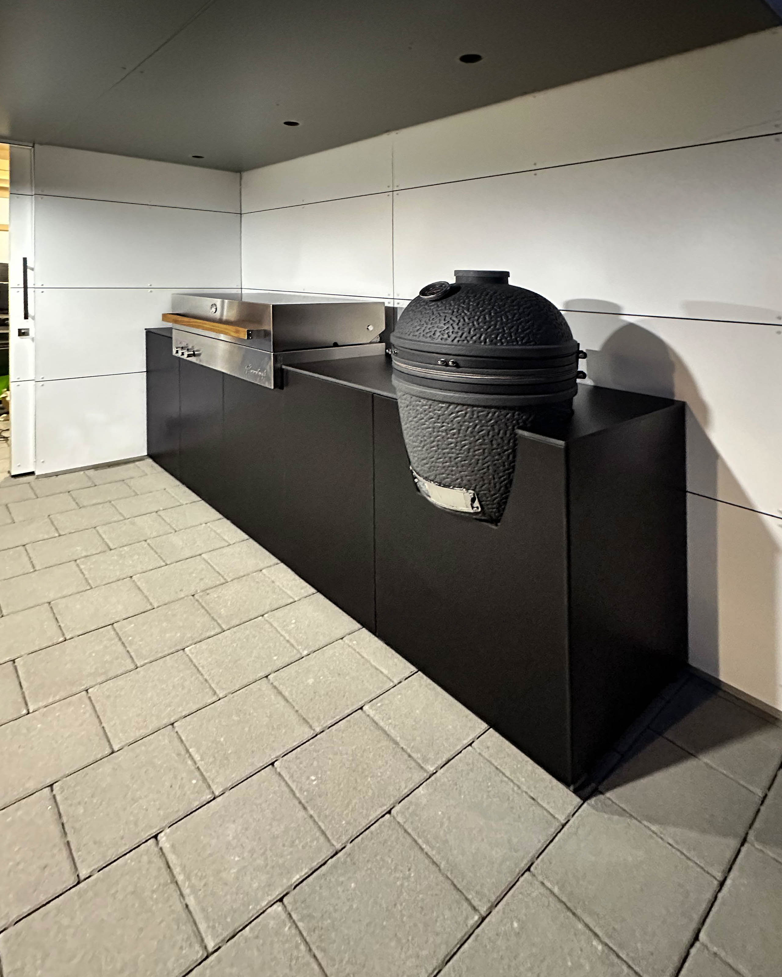 Cocina exterior negra con barbacoa empotrada Flammkraft y Big Green Egg 1