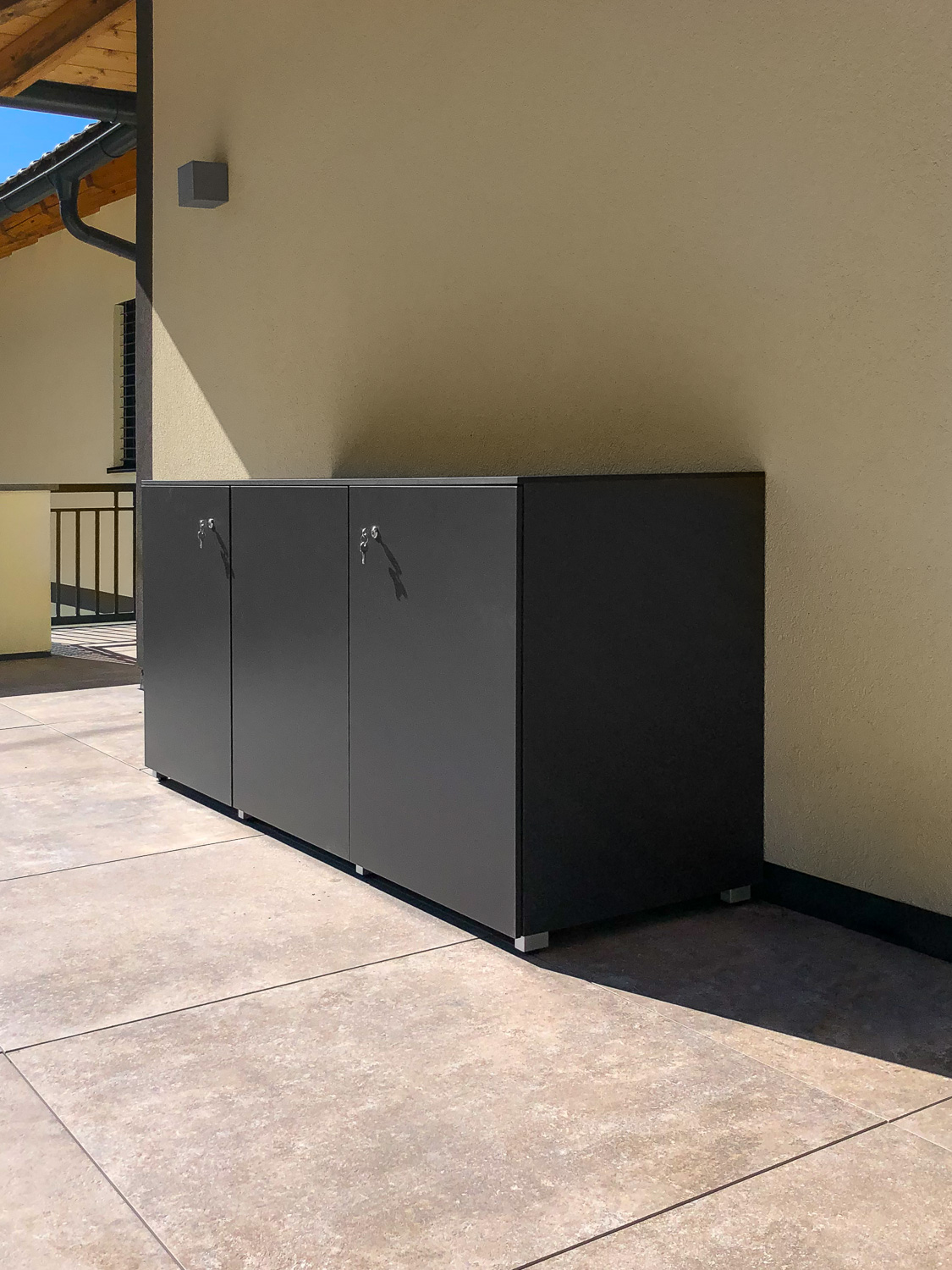 Outdoor Terrassenschrank in anthrazit vor gelber Hauswand