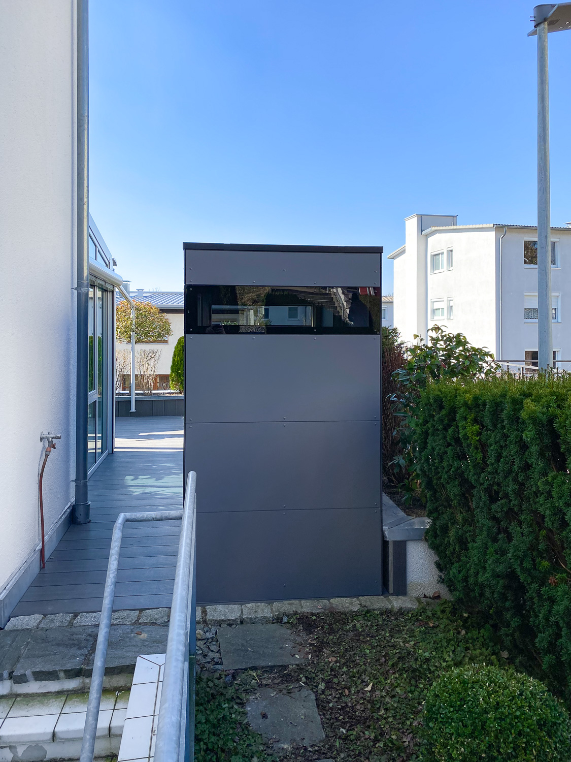 Schmales Gartenhaus neben Kellerabgang auf der Terrasse