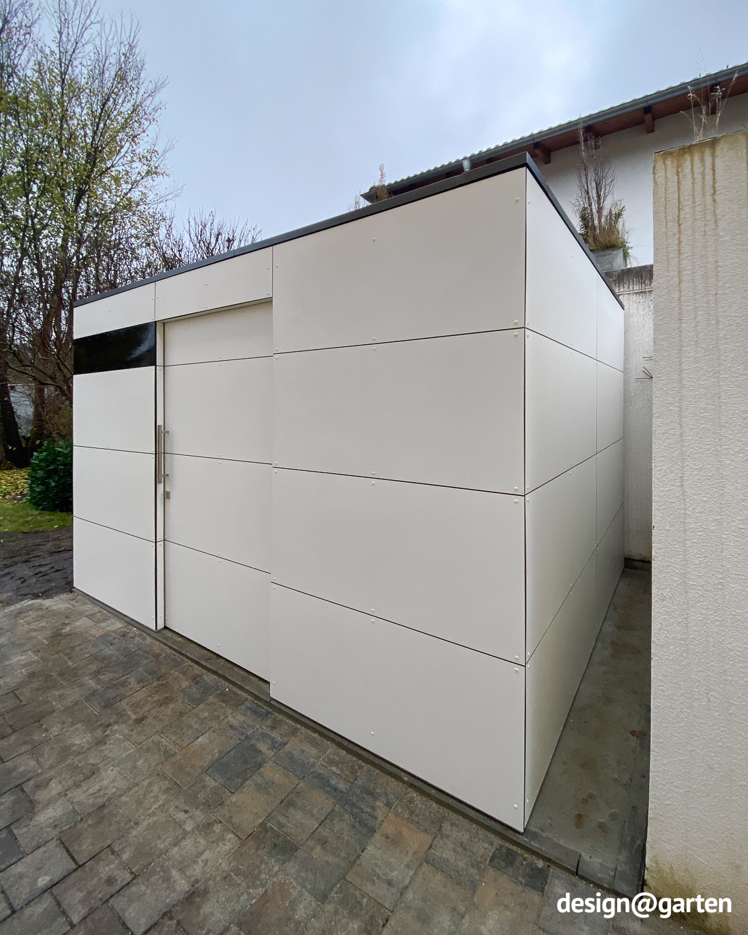 Abri de jardin blanc servant d'espace de rangement supplémentaire à côté d'un garage 2