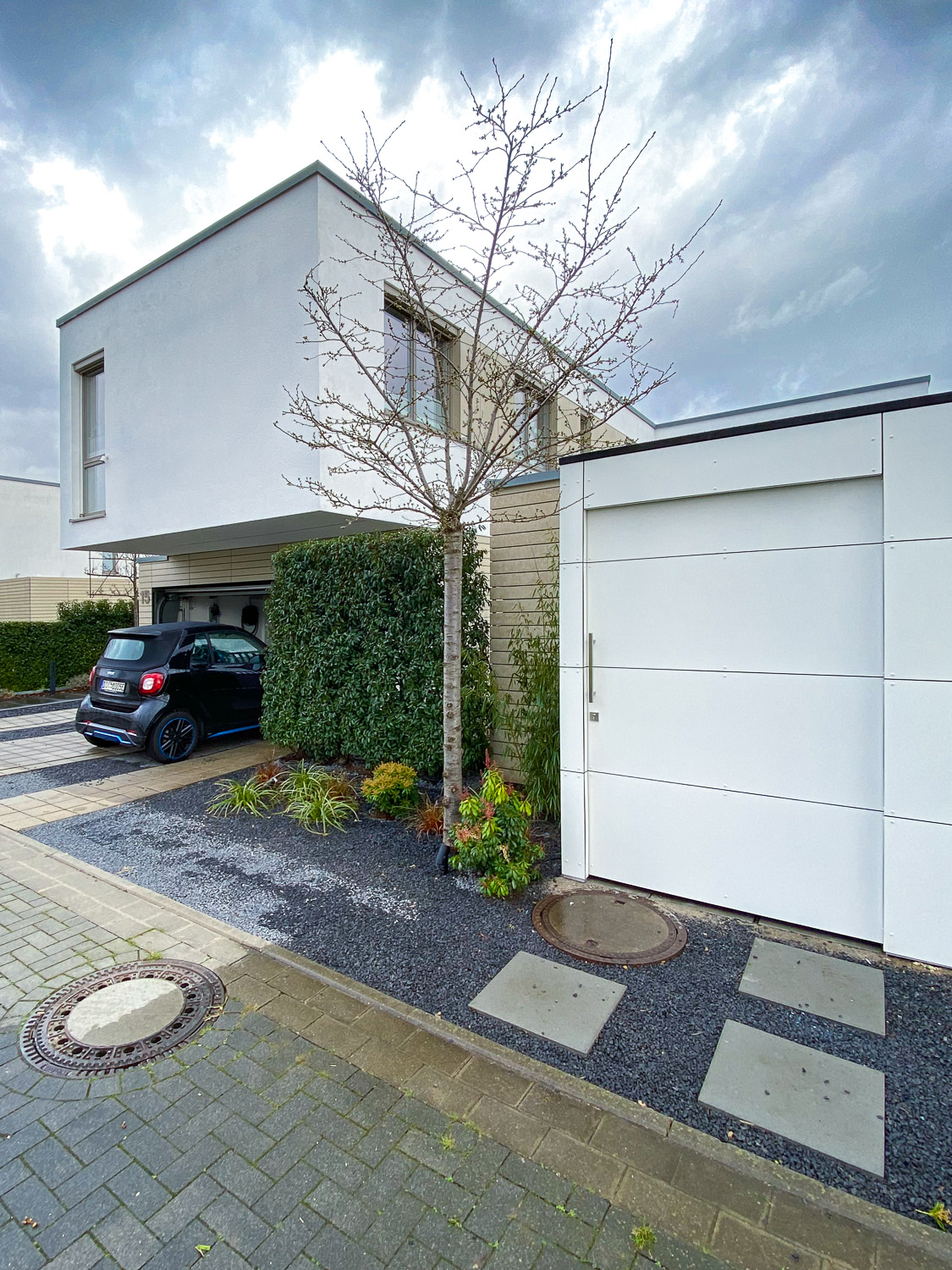 Weißes Gartenhaus neben moderner Architektur