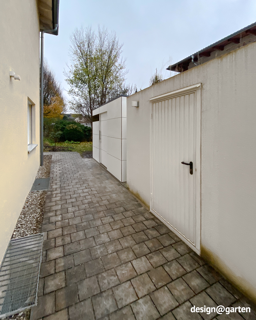 Casetta da giardino bianca come ampliamento dello spazio di stoccaggio accanto a un garage 1